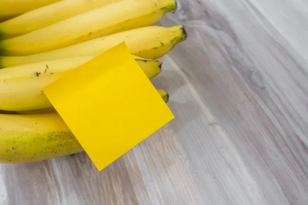 Banana com nota pegajosa na mesa de madeira  . — Fotografia de Stock