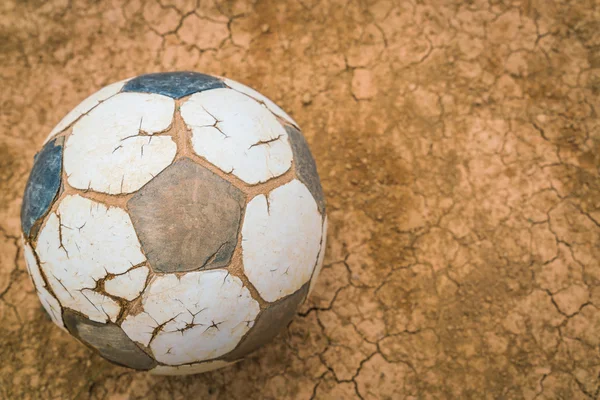 Old soccer ball on Dry and cracked ground texture . — Stock Photo, Image