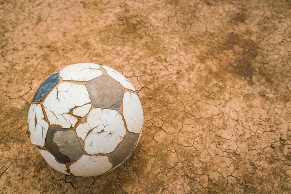 Old soccer ball on Dry and cracked ground texture . — Stock Photo, Image