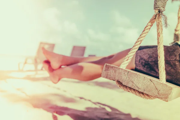 Mujer pierna en un columpio en la playa de mar tropical - Imagen filtrada proc — Foto de Stock