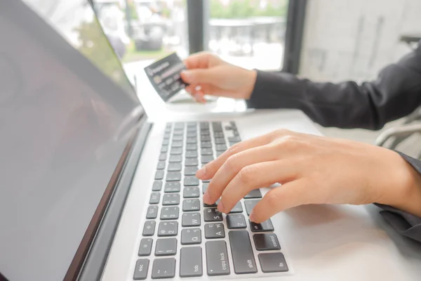 Mãos segurando um cartão de crédito e usando computador portátil para online — Fotografia de Stock