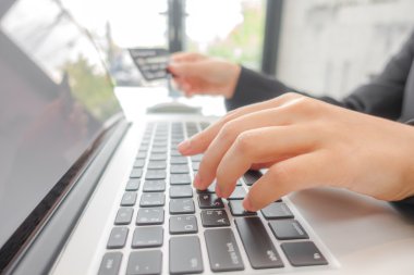 kredi kartı tutan ve dizüstü bilgisayar kullanarak çevrimiçi eller