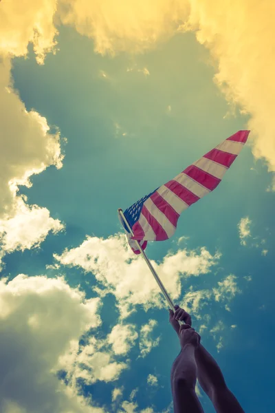 Bandera americana con estrellas y rayas sostienen con las manos contra blu — Foto de Stock