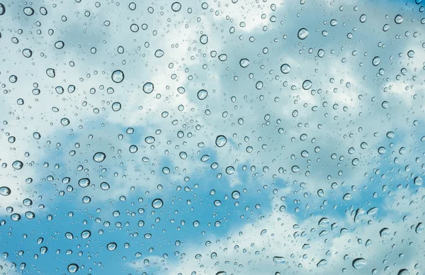 Des gouttes d'eau sur une fenêtre en verre au-dessus du ciel bleu  . — Photo