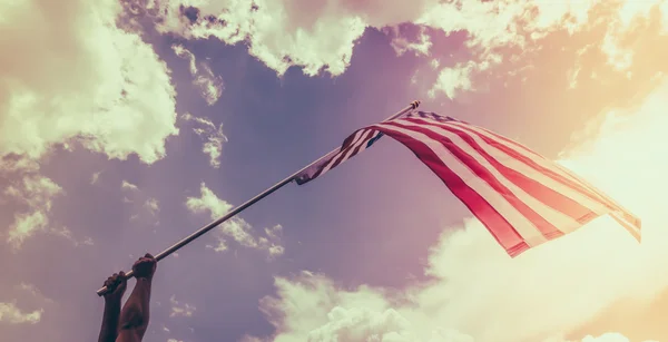 Bandera americana con estrellas y rayas sostienen con las manos contra blu — Foto de Stock