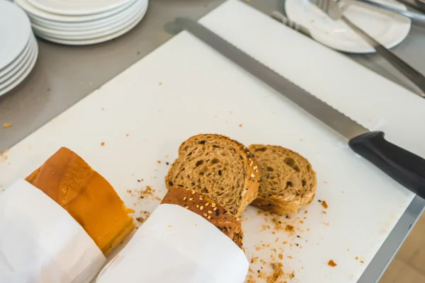 Rebanada de pan fresco y cuchillo de corte en la mesa en buffet  . — Foto de Stock