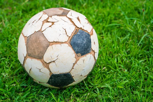 Starý fotbalový míč na čerstvé jarní zelené trávě — Stock fotografie