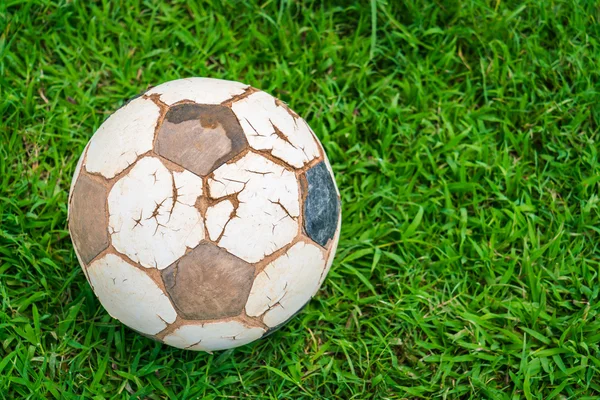 Starý fotbalový míč na čerstvé jarní zelené trávě — Stock fotografie