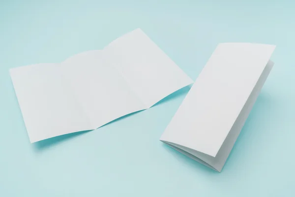 Potrójnie składany papier do szablonu biały na niebieskim tle . — Zdjęcie stockowe