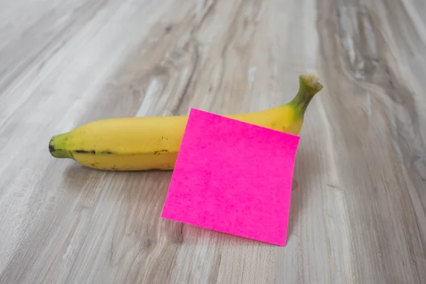 Banana con nota adesiva su tavolo in legno  . — Foto Stock