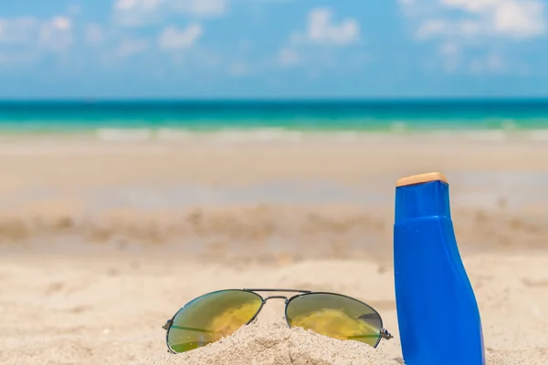 Occhiali da sole e crema solare sulla spiaggia di sabbia bianca — Foto Stock