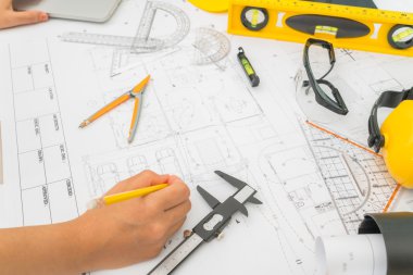 Sarı kask ve çizim aracı ile inşaat planları teslim