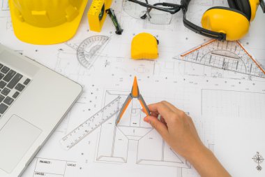 Sarı kask ve çizim aracı ile inşaat planları teslim