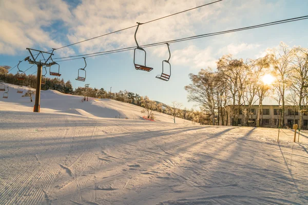 Pôr-do-sol e elevador de esqui passando pela montanha — Fotografia de Stock