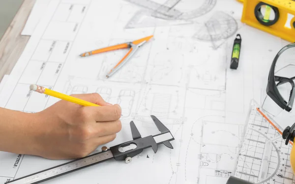 Entregar planos de construção com capacete amarelo e ferramenta de desenho — Fotografia de Stock
