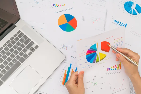 Zakelijke vrouw hand met financiële grafieken en laptop op de ta — Stockfoto