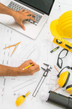 Sarı kask ve çizim aracı ile inşaat planları teslim