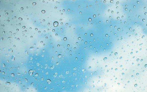 Waterdruppels op de glazen venster over blauwe hemel . — Stockfoto