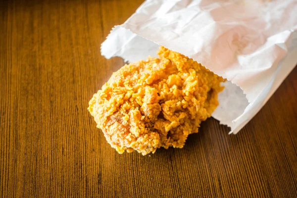 Asas de frango frito em saco de papel na mesa de madeira  . — Fotografia de Stock