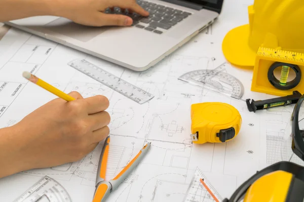 Entregar planos de construção com capacete amarelo e ferramenta de desenho — Fotografia de Stock