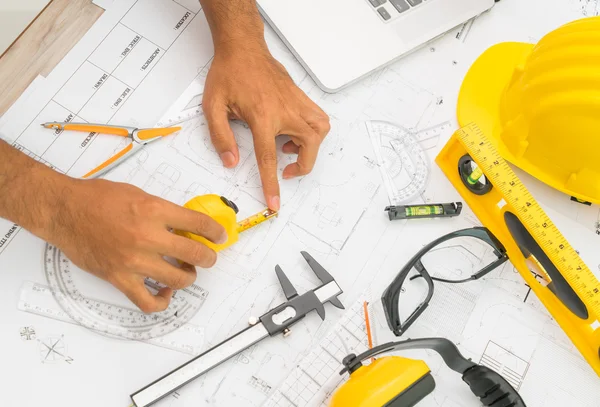 Entregar planos de construção com capacete amarelo e ferramenta de desenho — Fotografia de Stock