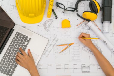 Sarı kask ve çizim aracı ile inşaat planları teslim