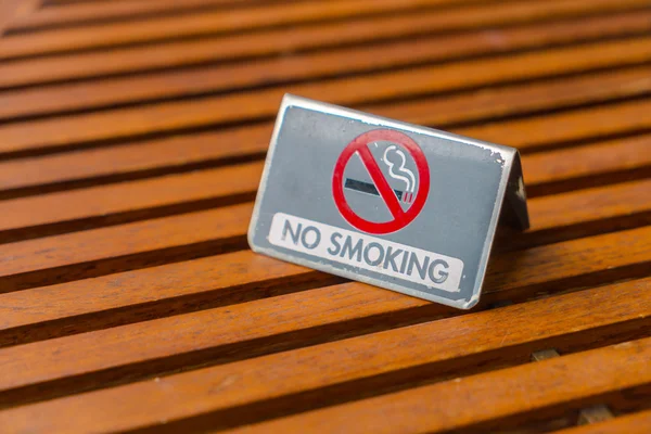 NO Smoking sign on wood table .