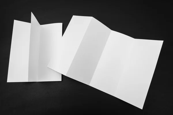 Vier - vouwen wit sjabloon papier op zwarte achtergrond . — Stockfoto