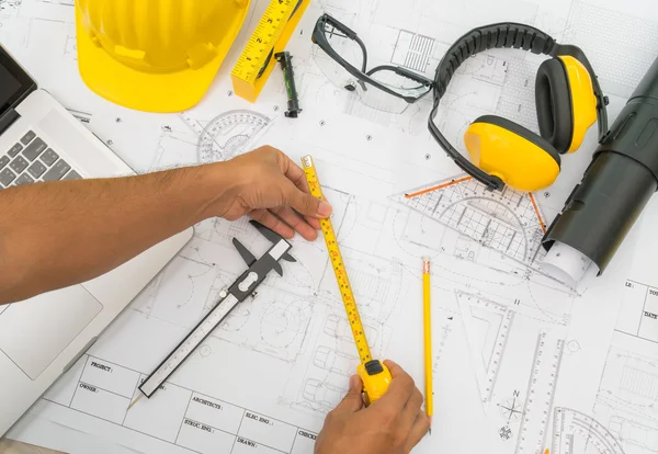 Entregar planos de construcción con casco amarillo y herramienta de dibujo — Foto de Stock