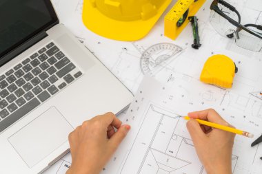 Sarı kask ve çizim aracı ile inşaat planları teslim