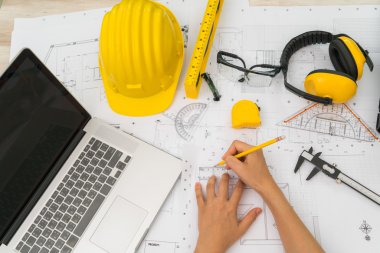 Sarı kask ve çizim aracı ile inşaat planları teslim
