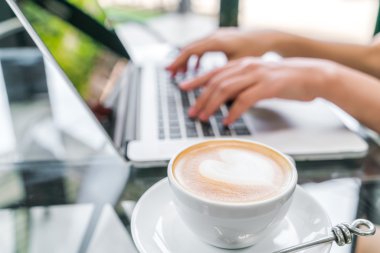 Closeup Latte Kahve sanat ve kadın el laptop keya yazma