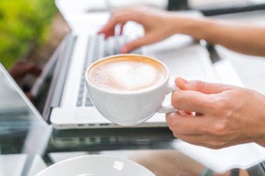 Closeup Latte Kahve sanat ve kadın el laptop keya yazma