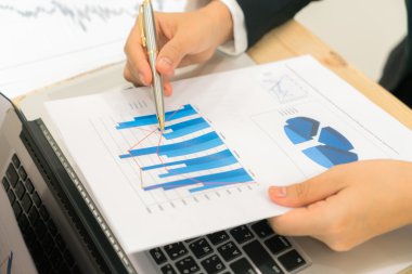 Kapalı toplantıda laptop ve mali grafikleri kullanarak iş adamları