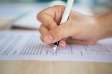 Close up of hand completing an employment application form clipart
