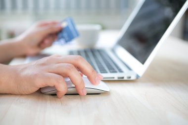 kredi kartı tutan ve dizüstü bilgisayar kullanarak çevrimiçi eller