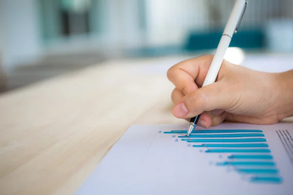Hand skriva på olika finansiella diagram på bordet — Stockfoto