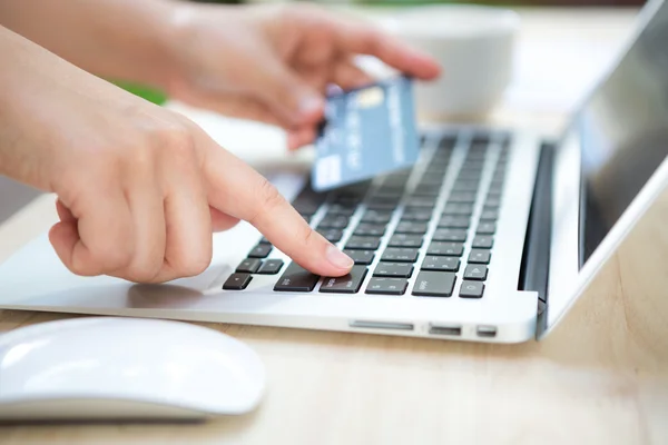 Mãos segurando um cartão de crédito e usando computador portátil para online — Fotografia de Stock