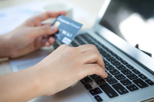 Mãos segurando um cartão de crédito e usando computador portátil para online — Fotografia de Stock