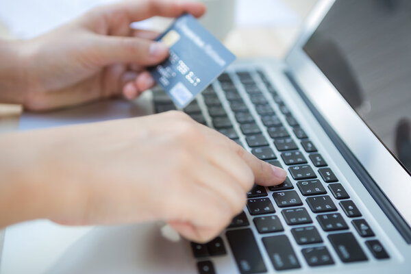 Manos sosteniendo una tarjeta de crédito y el uso de ordenador portátil para en línea — Foto de Stock