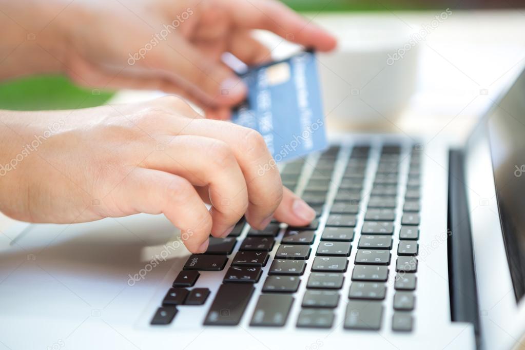 Hands holding a credit card and using laptop computer for online