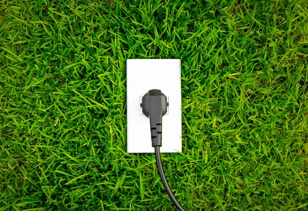 Energy concept outlet in fresh spring green grass — Stock Photo, Image