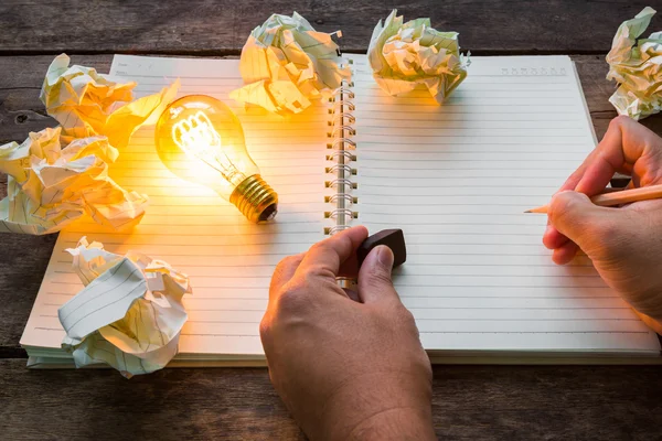 Hand write over Note book and light bulb on wood table — Stock Photo, Image
