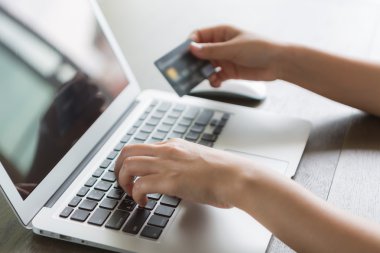 kredi kartı tutan ve dizüstü bilgisayar kullanarak çevrimiçi eller
