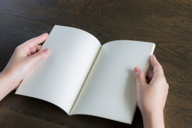 Ahşap masa üzerinde eller açık kitap