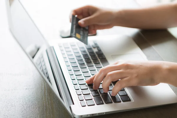 Mãos segurando um cartão de crédito e usando computador portátil para online — Fotografia de Stock