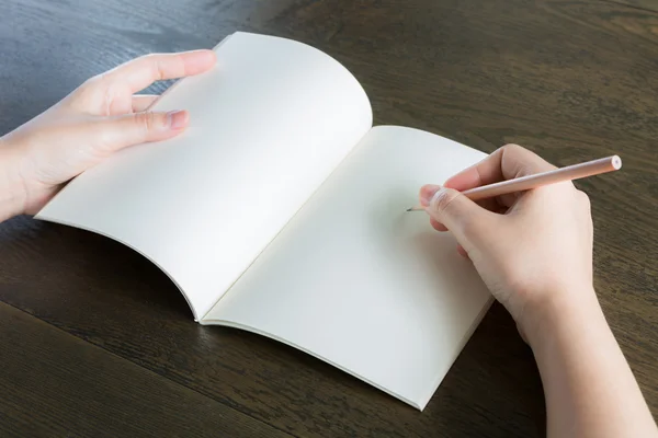 Handen met potlood en boek over houten tafel — Stockfoto