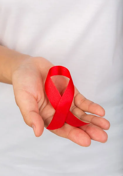 Mãos femininas segurando fita vermelha da consciência da AIDS — Fotografia de Stock