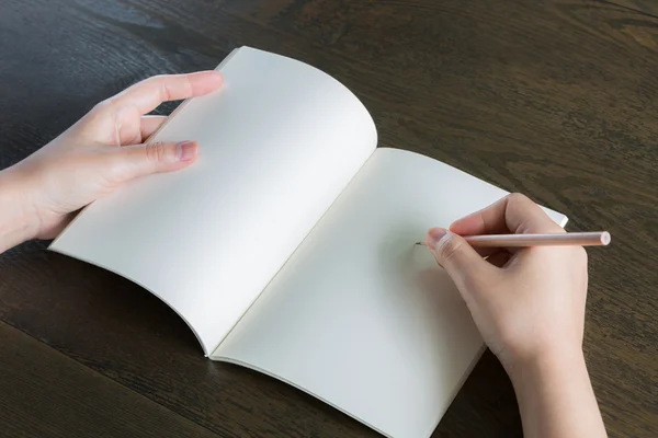 Handen met potlood en boek over houten tafel — Stockfoto