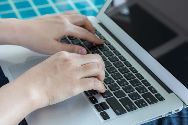 Vrouw die werkt met laptopcomputer zitten bij zwembad — Stockfoto